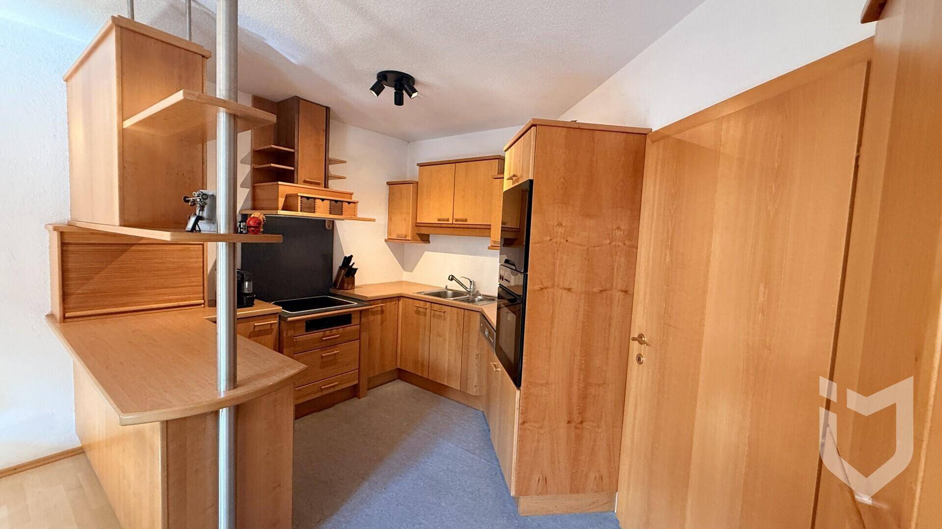 Gemütliche Küche mit Holzfronten, integrierten Geräten und einer praktischen Frühstückstheke.