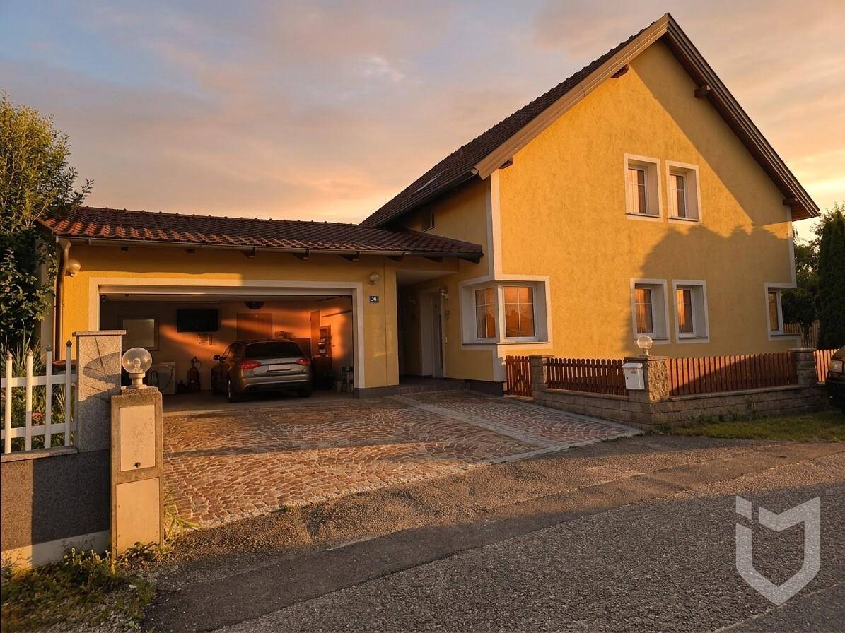 Einfamilienhaus mit Garage und Einfahrt im warmen Licht der untergehenden Sonne.
