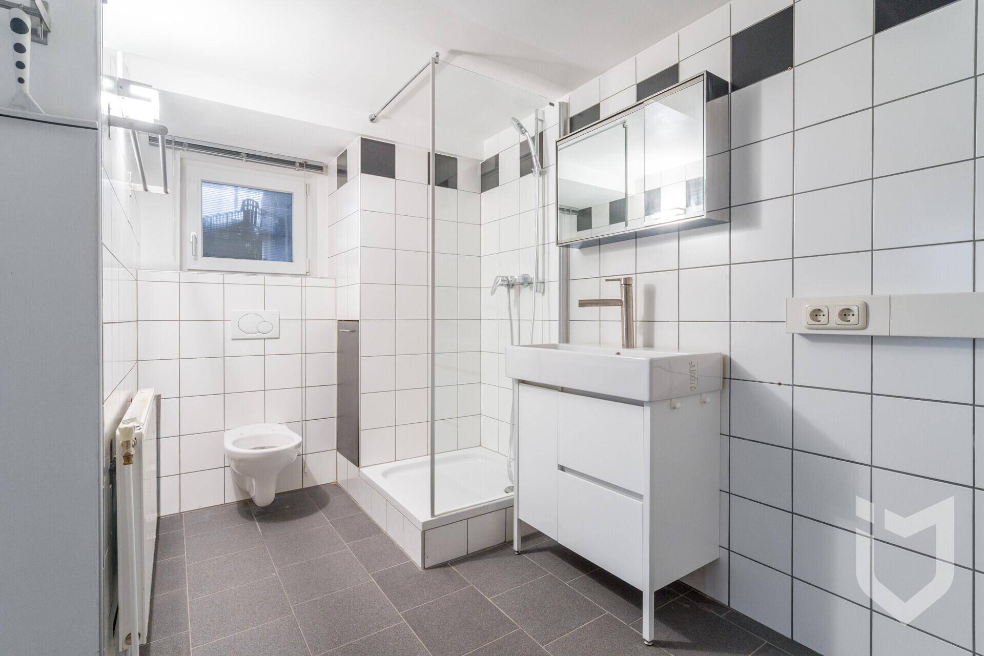 Modernes Badezimmer im Untergeschoss mit Dusche, WC und Einzelwaschbecken.
