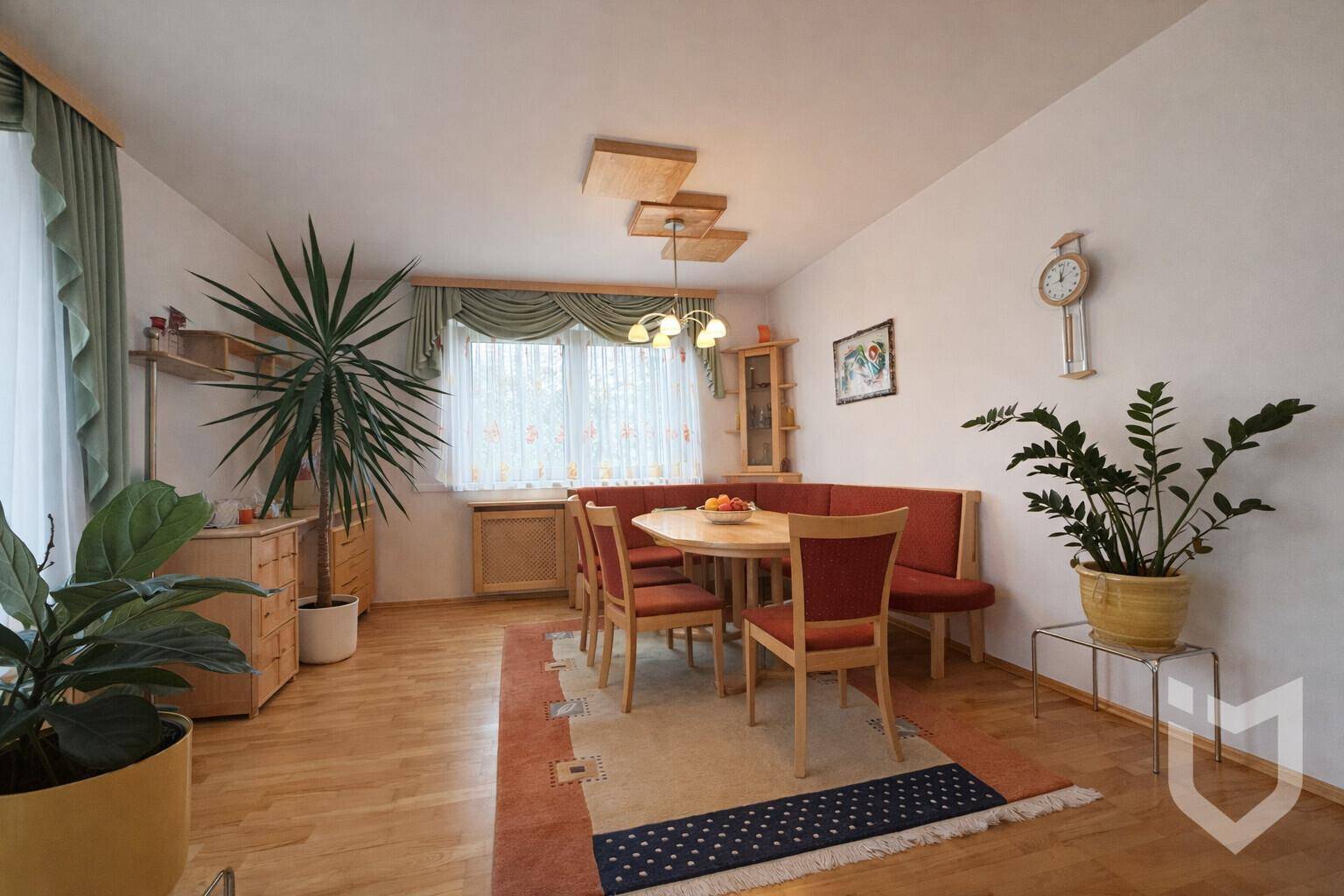 Heller Essbereich mit Eckbank, Holztisch und Stühlen, ergänzt durch einen Teppich und Pflanzen.