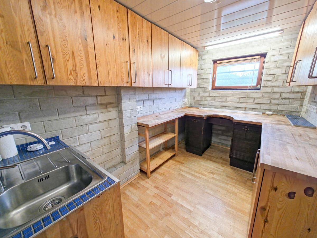 Rustikale Küche mit Holzschränken, Arbeitsplatten und gemauerter Rückwand.