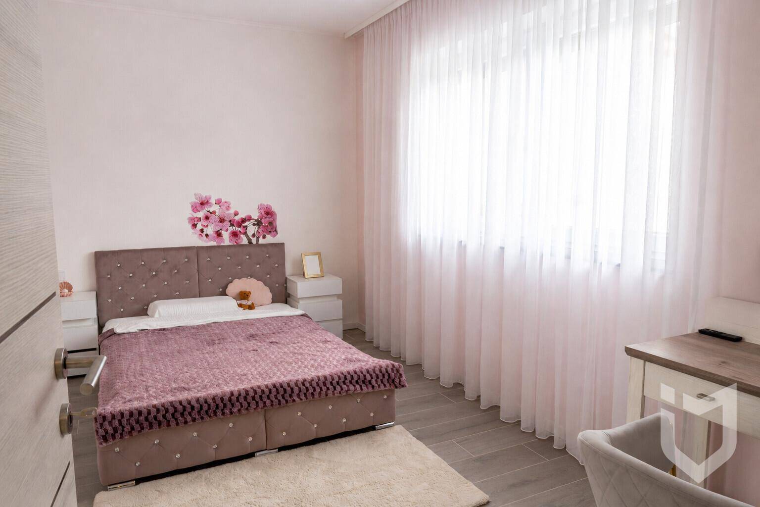 Mädchenzimmer mit rosa Bett, floraler Wanddekoration und viel Tageslicht.