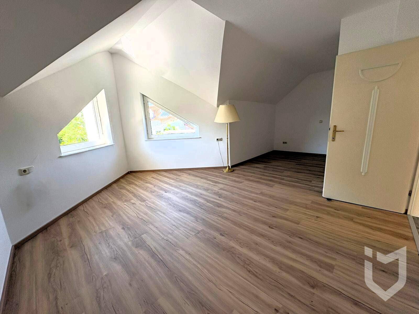 Schlafzimmer im Dachgeschoss mit Laminatboden und schrägen Wänden.