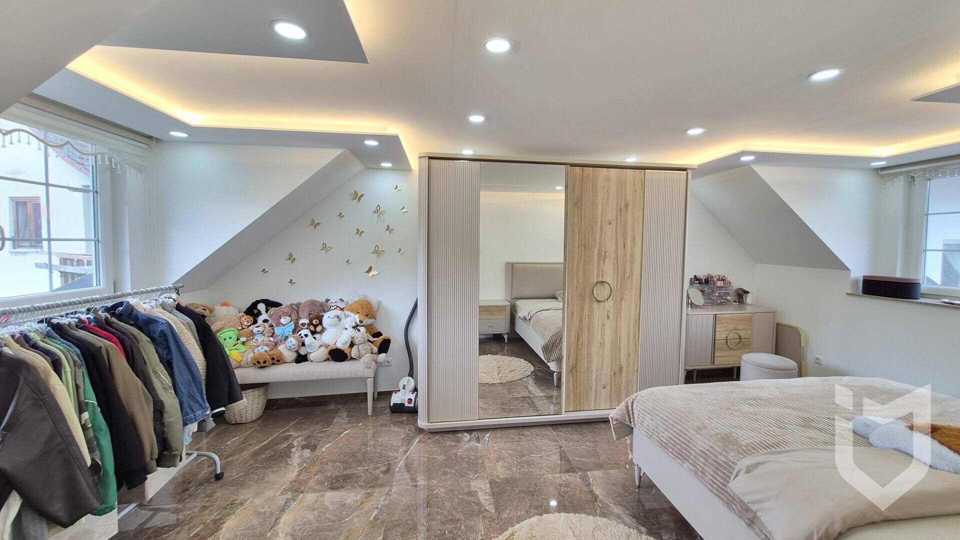 Geräumiges Schlafzimmer im Dachgeschoss mit Kleiderschrank, Stauraum und moderner Einrichtung.