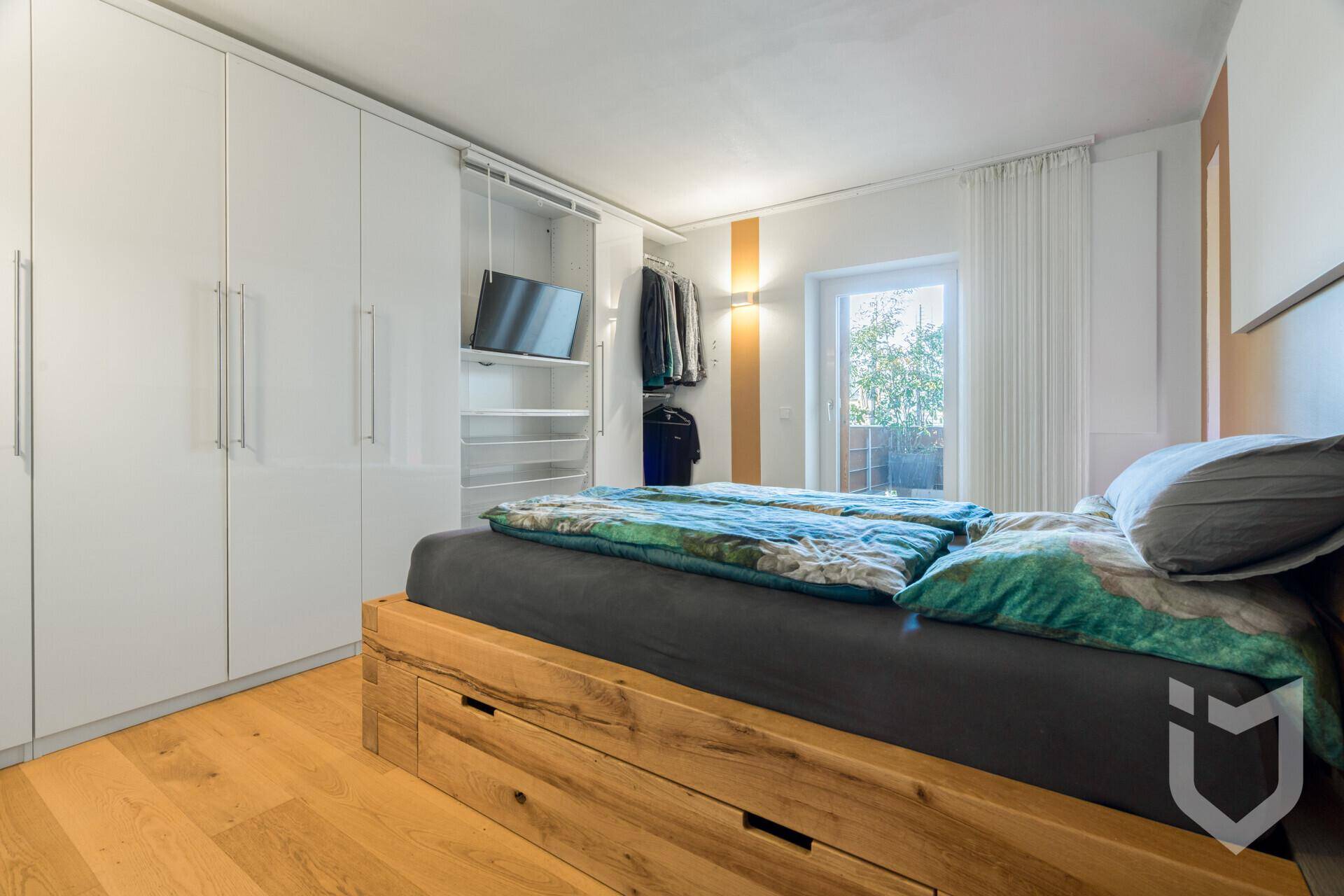 Schlafzimmer mit Holzbett, Einbauschränken und hellem Holzboden.