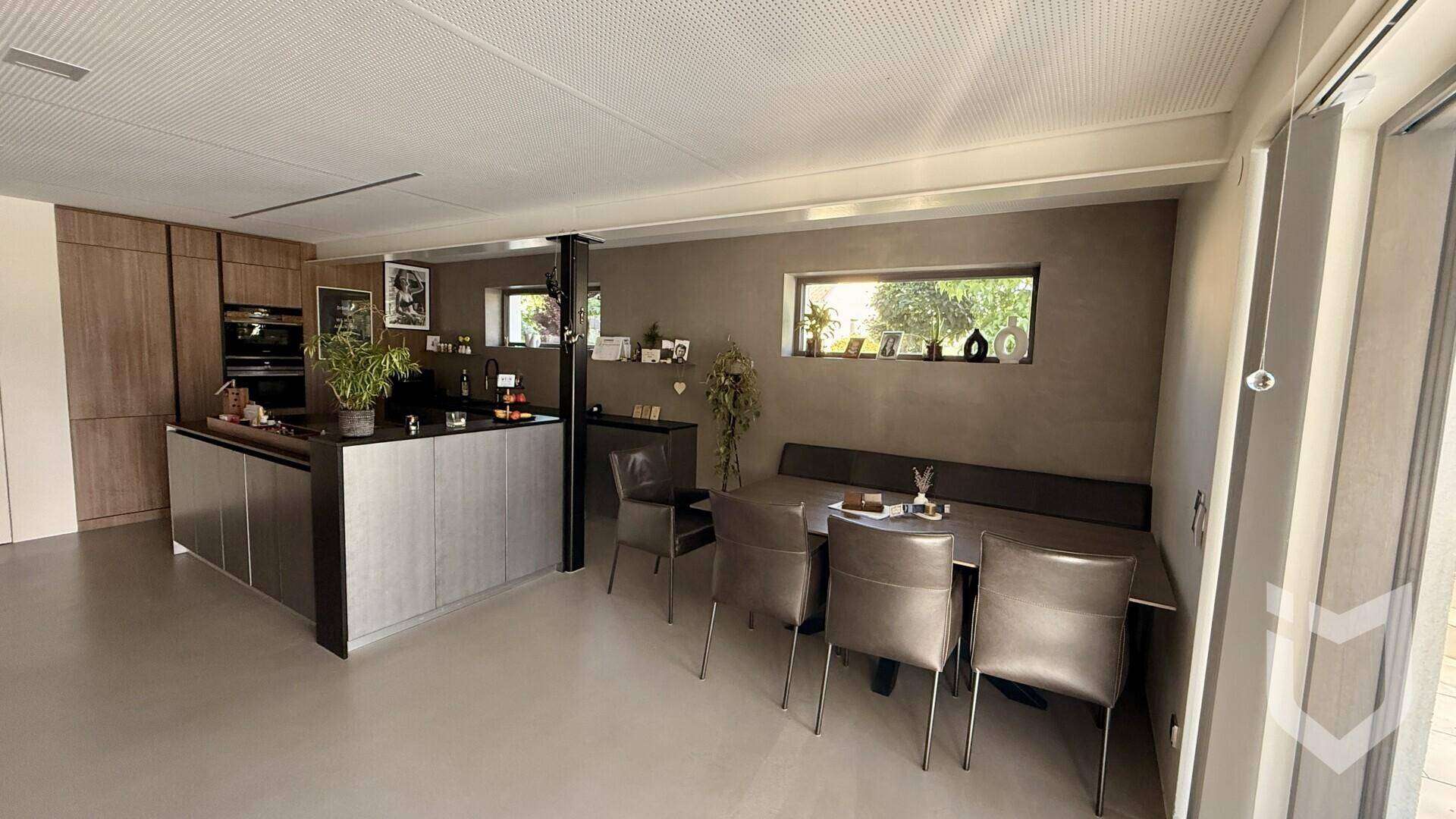 Moderne offene Küche mit dunklen Schränken, integriertem Essbereich und minimalistischem Design.