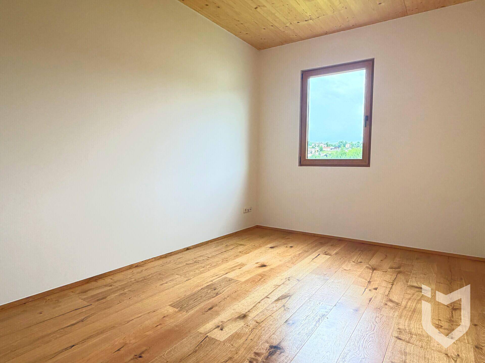 Helles Zimmer mit Holzboden und Holzdecke, bietet einen weiten Blick über die umliegende Landschaft.