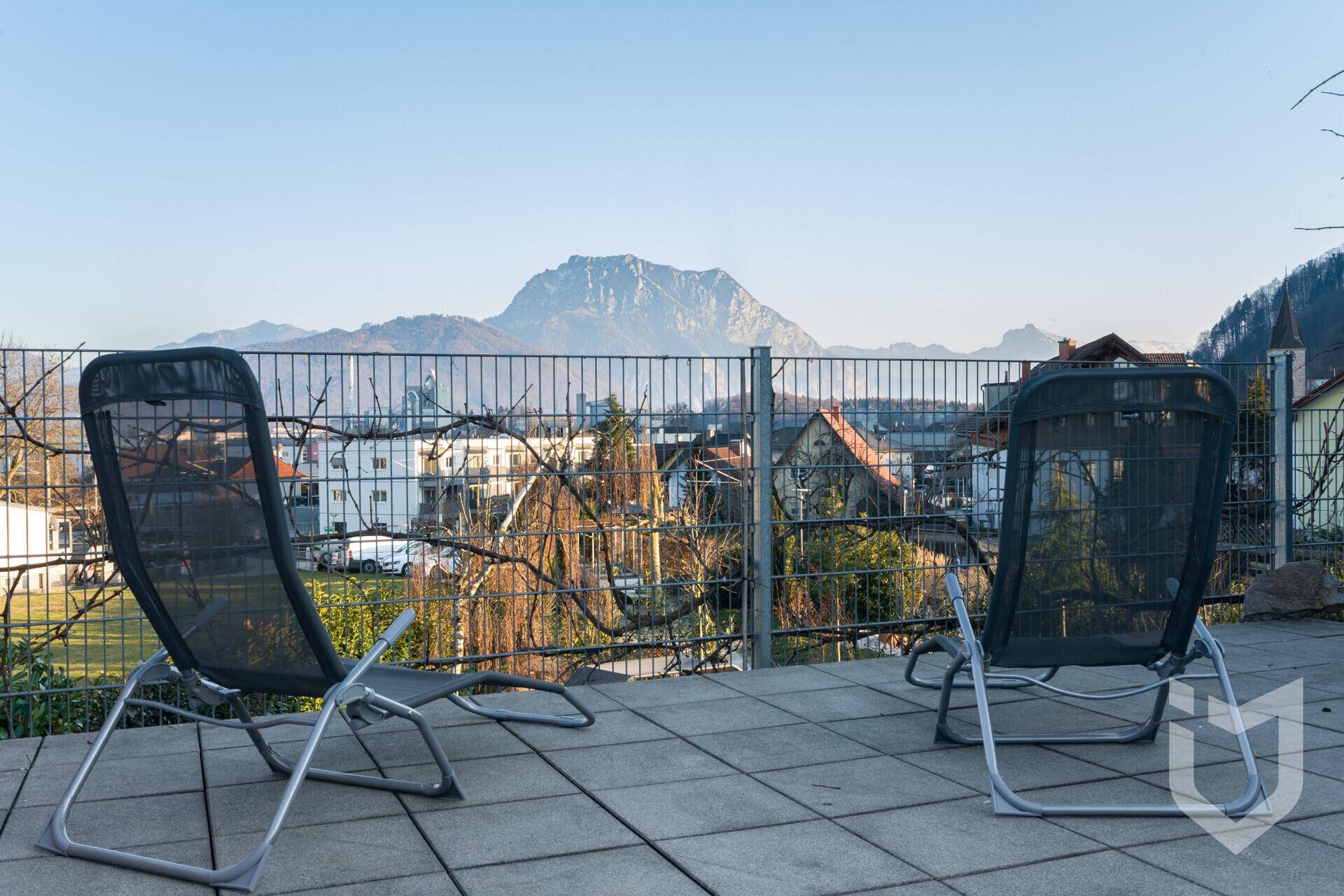 Sonniger Terrassenbereich mit Liegestühlen und weitem Bergblick.