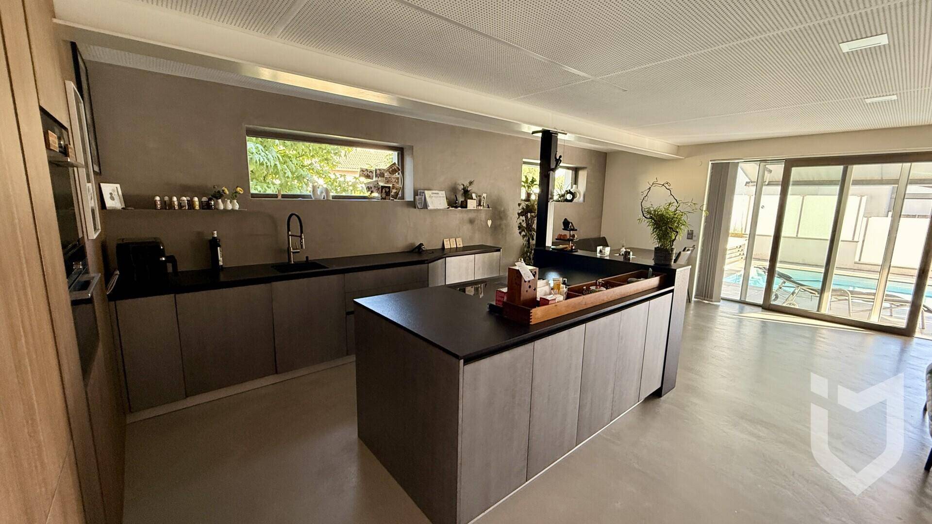 Geräumige, moderne Küche mit Kochinsel und direktem Zugang zum Außenbereich mit Poolblick.