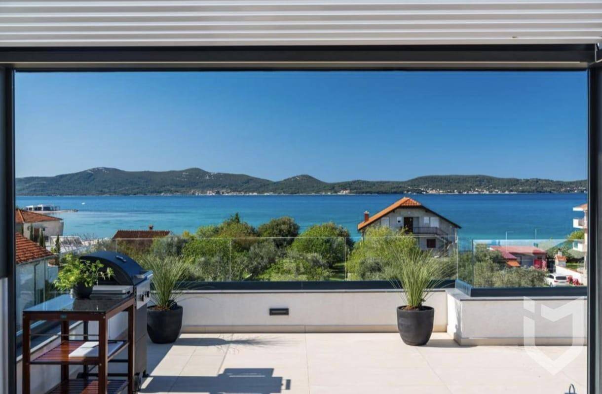Weitläufige Dachterrasse mit Grillbereich, Pflanzen und atemberaubendem Meerblick.