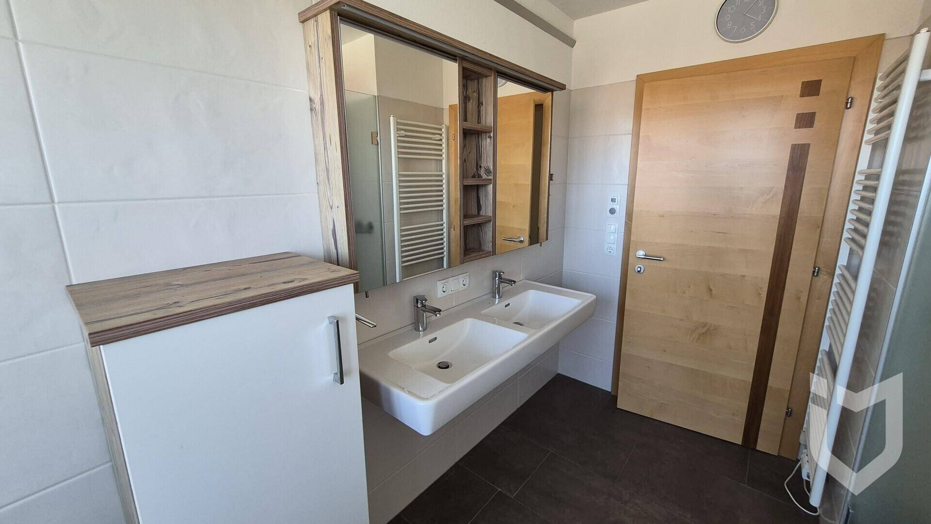 Modernes Badezimmer mit Doppelwaschbecken, Spiegelschrank und beheiztem Handtuchhalter.