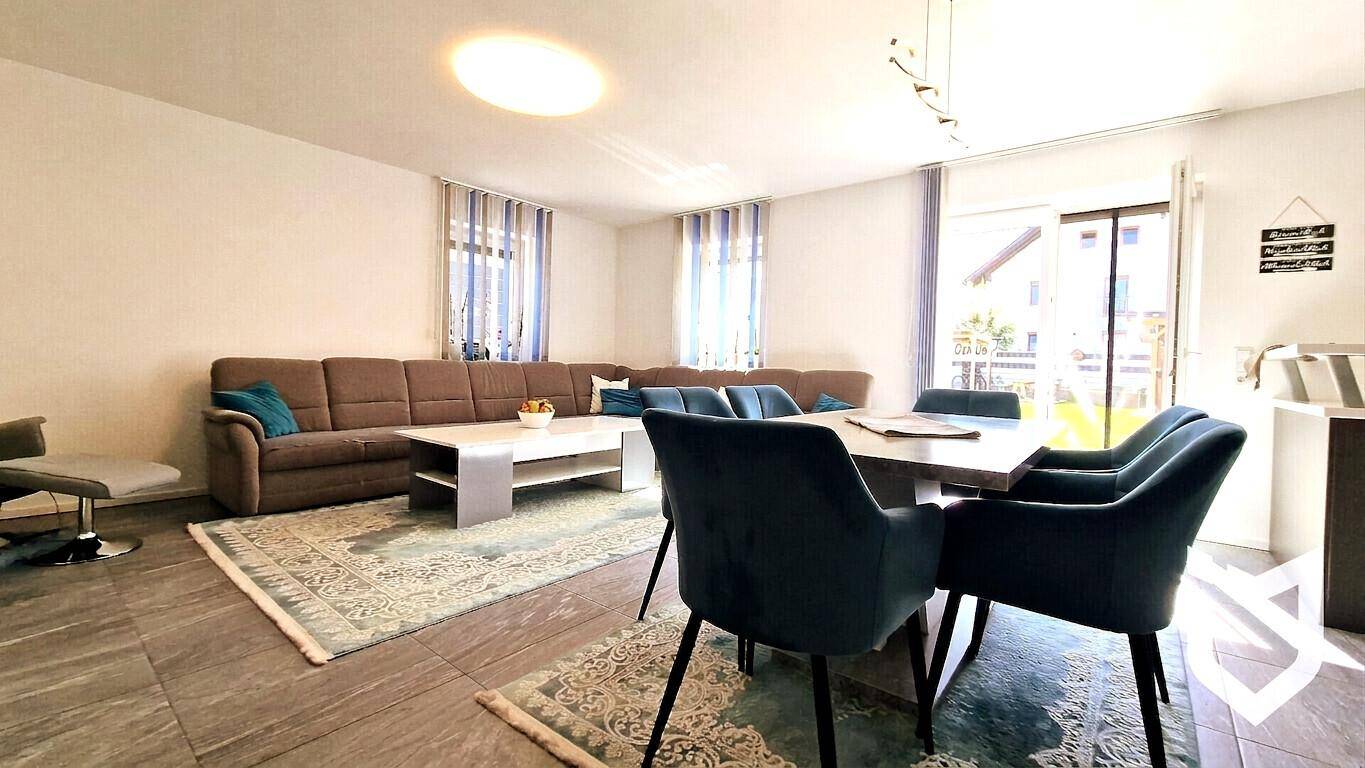 Gemütlicher Wohn- und Essbereich mit großem Sofa und eleganten blauen Stühlen.