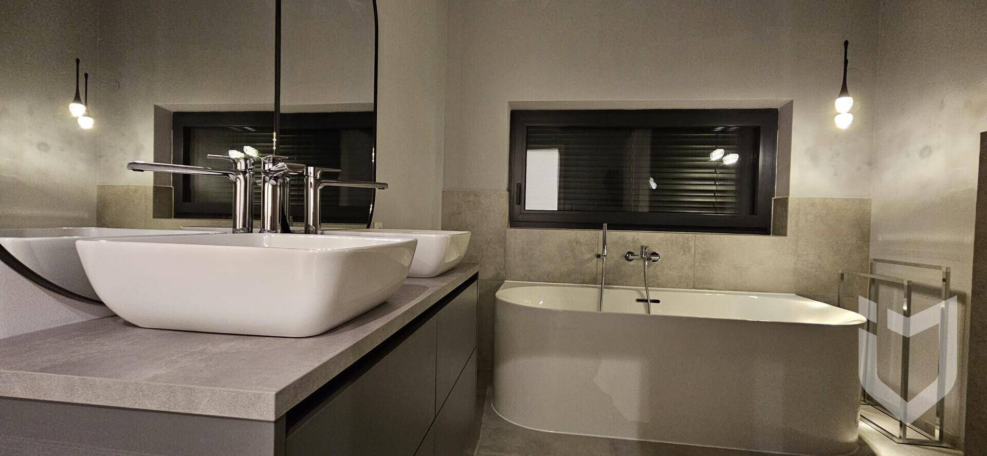 Modernes Badezimmer mit Doppelwaschbecken, freistehender Badewanne und stilvoller Beleuchtung.