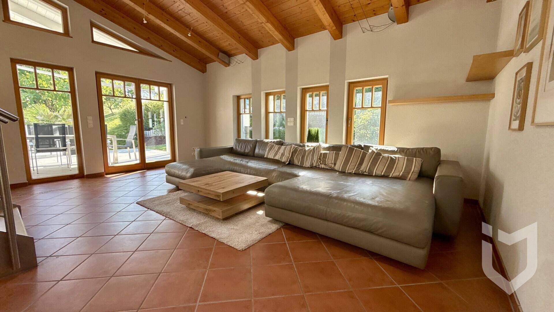 Weitläufiges Wohnzimmer mit gemütlichem Sofa, warmen Terrakottafliesen und viel Tageslicht.