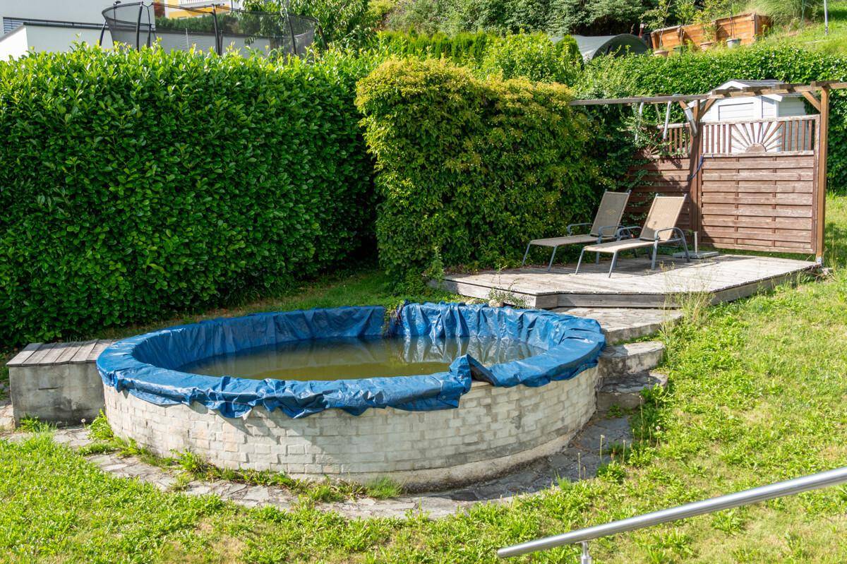 Gartenbereich mit einem runden Aufstellpool und einer kleinen Sonnenterrasse.