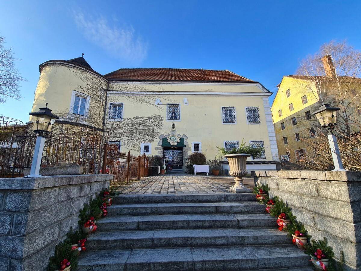 Historisches Gebäude mit festlich geschmücktem Eingangsbereich und Steintreppe unter blauem Himmel.
