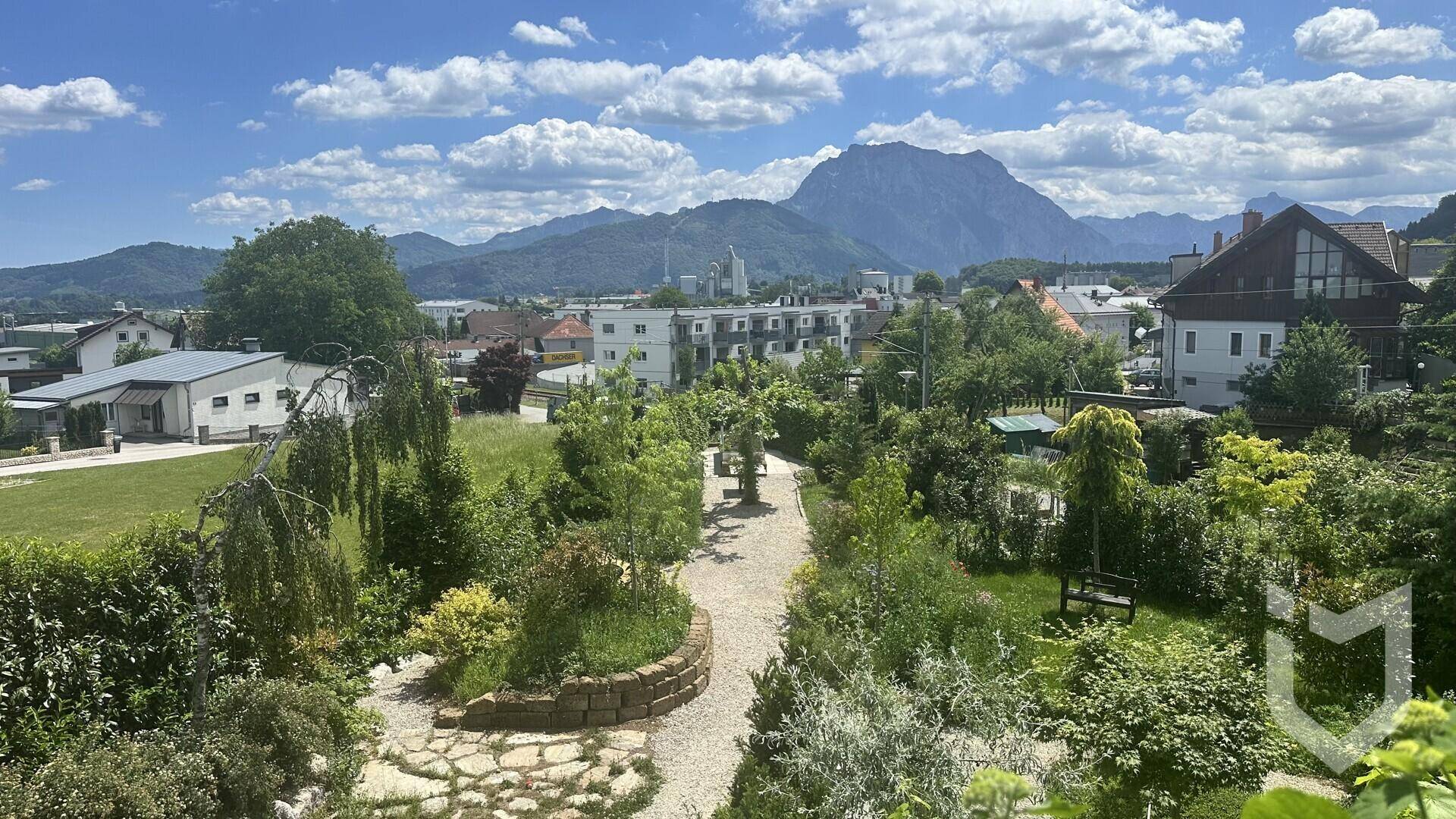 Großer Garten mit Bergblick, Wegen und vielfältiger Bepflanzung.