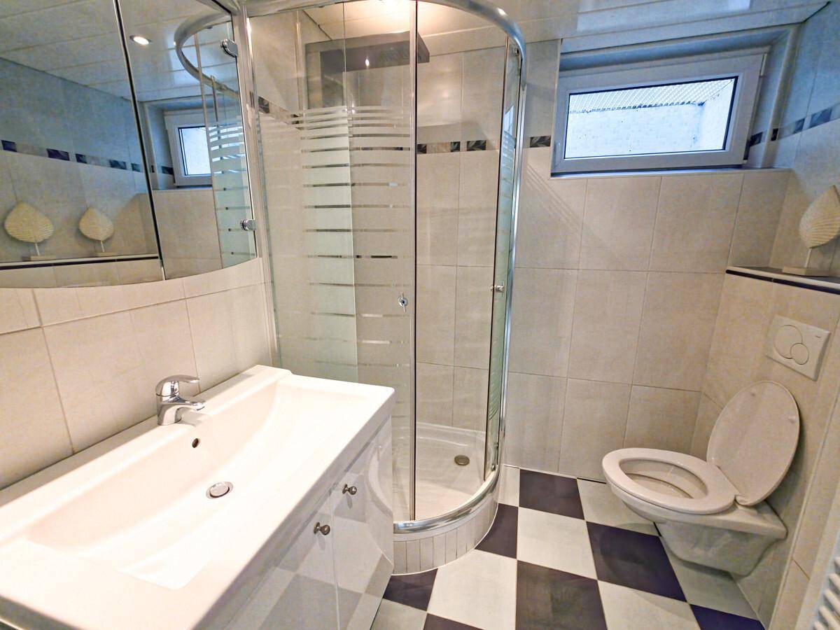 Modernes Badezimmer mit Duschkabine, Waschbecken und WC, ausgestattet mit Fliesenboden.
