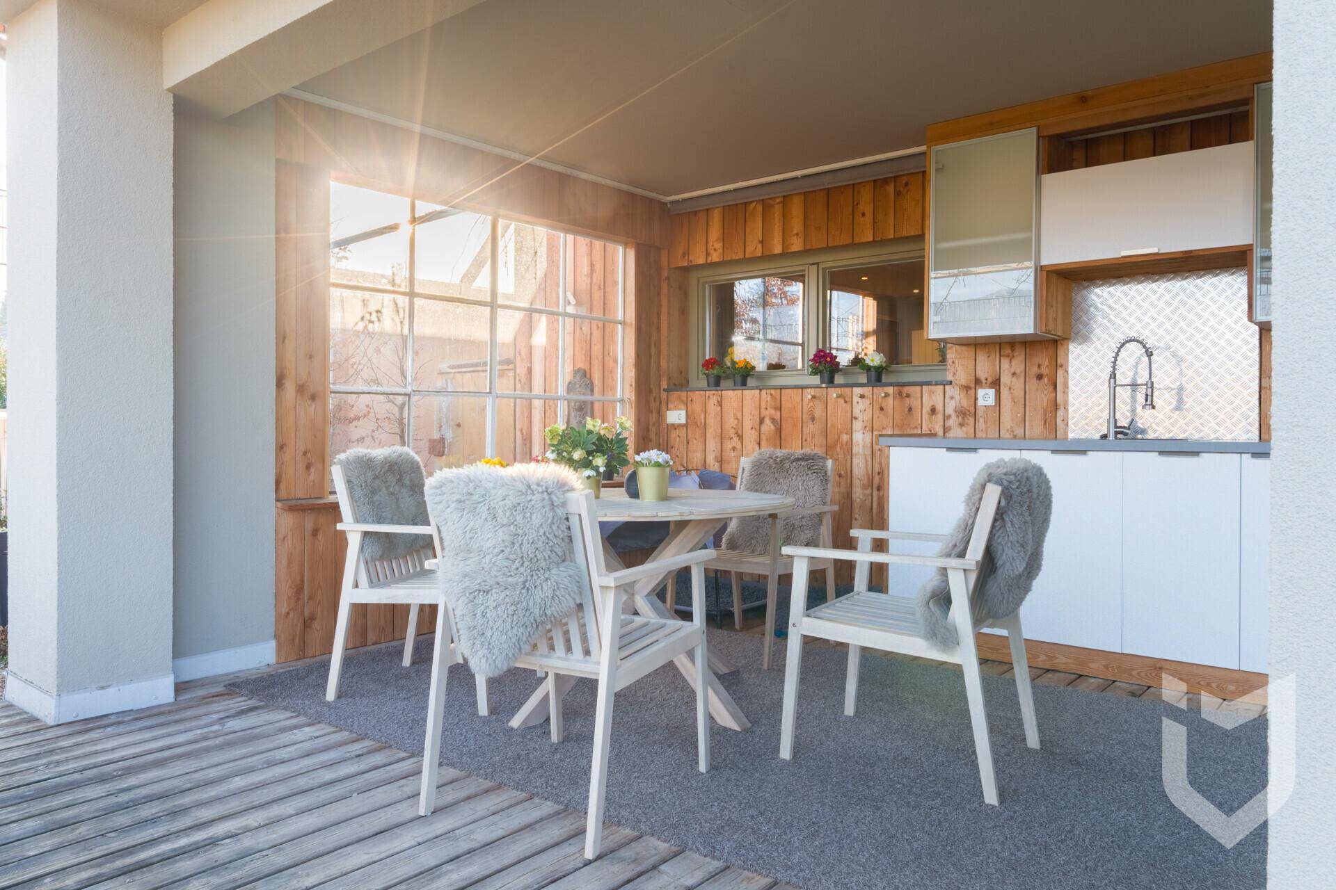 Überdachte Terrasse mit Holzwänden, Essbereich und Außenküche.