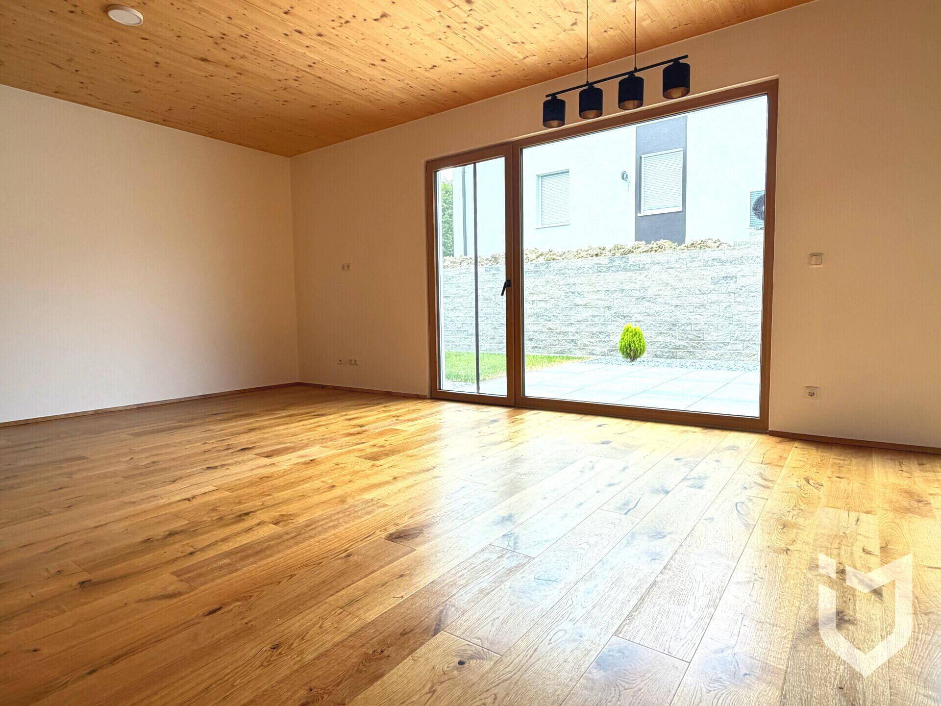 Heller Wohnraum mit Holzboden und großer Glasschiebetür zum Außenbereich, bereit zur individuellen Gestaltung.