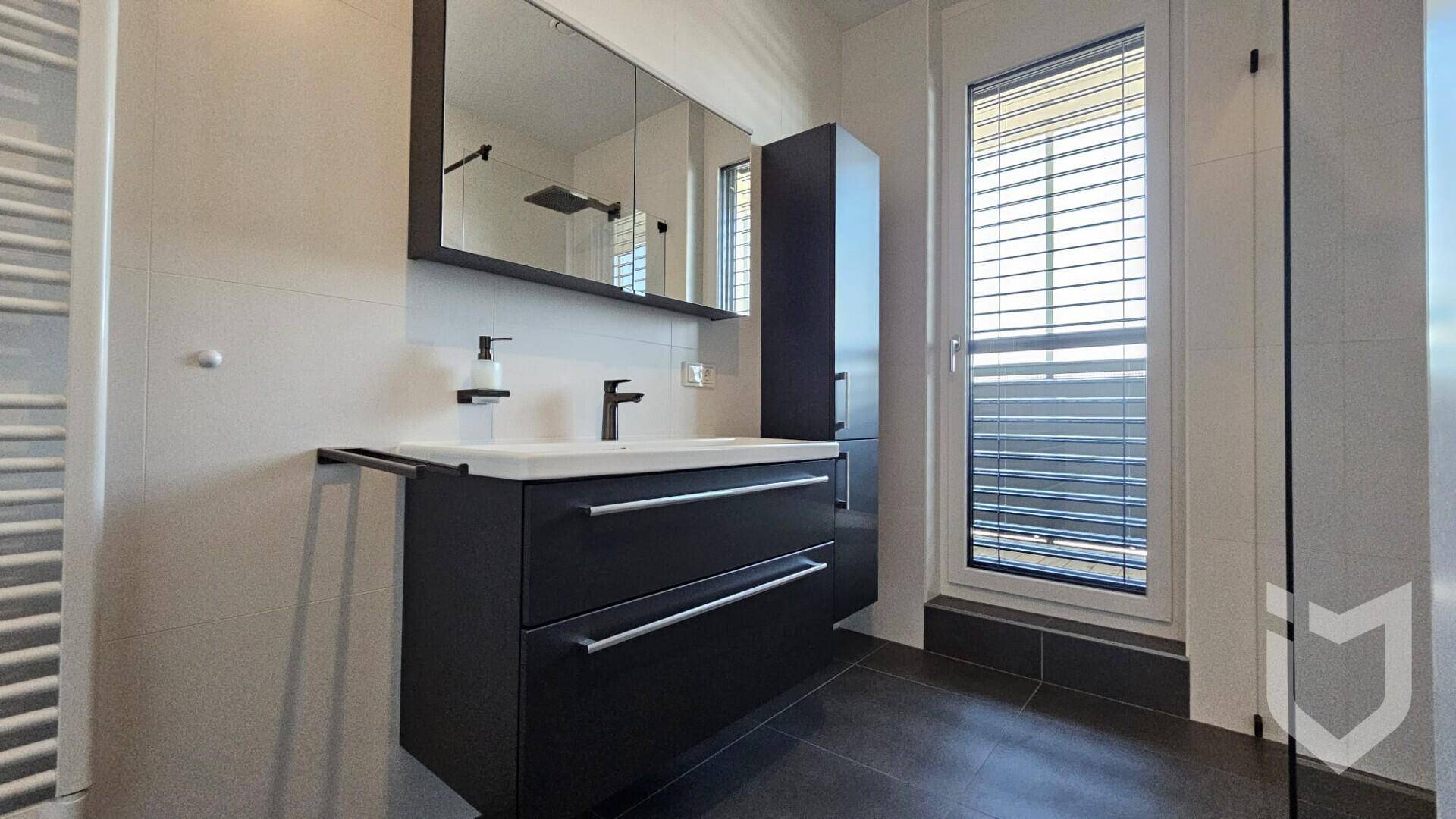 Modernes Badezimmer mit dunklem Waschtisch, Spiegelschrank, ebenerdiger Dusche und Fenster.