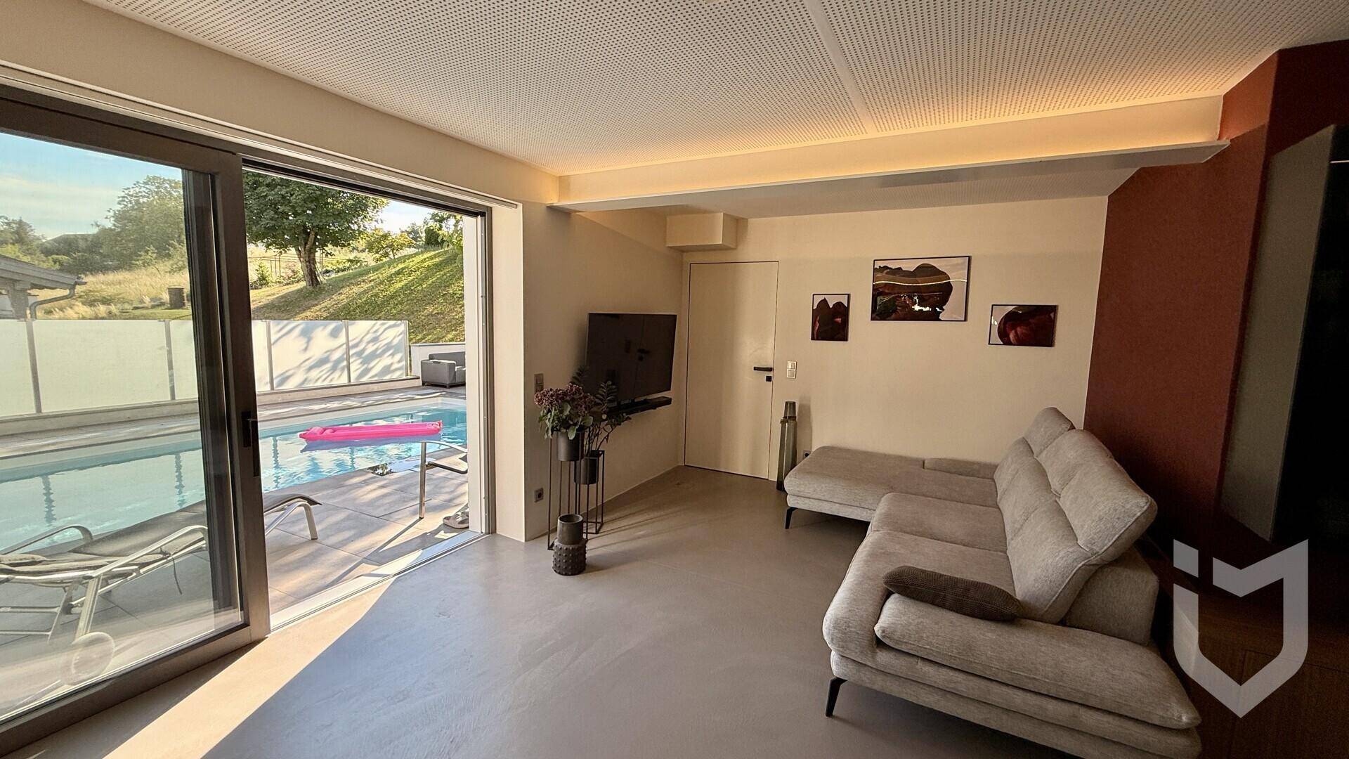 Helles Wohnzimmer mit gemütlichem Sofa und großen Schiebetüren zum privaten Poolbereich.
