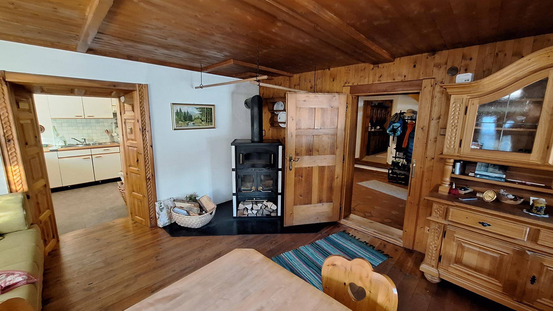 Wohnbereich mit Holzboden, Holzdecke und einem gemütlichen Holzofen, der Wärme spendet.