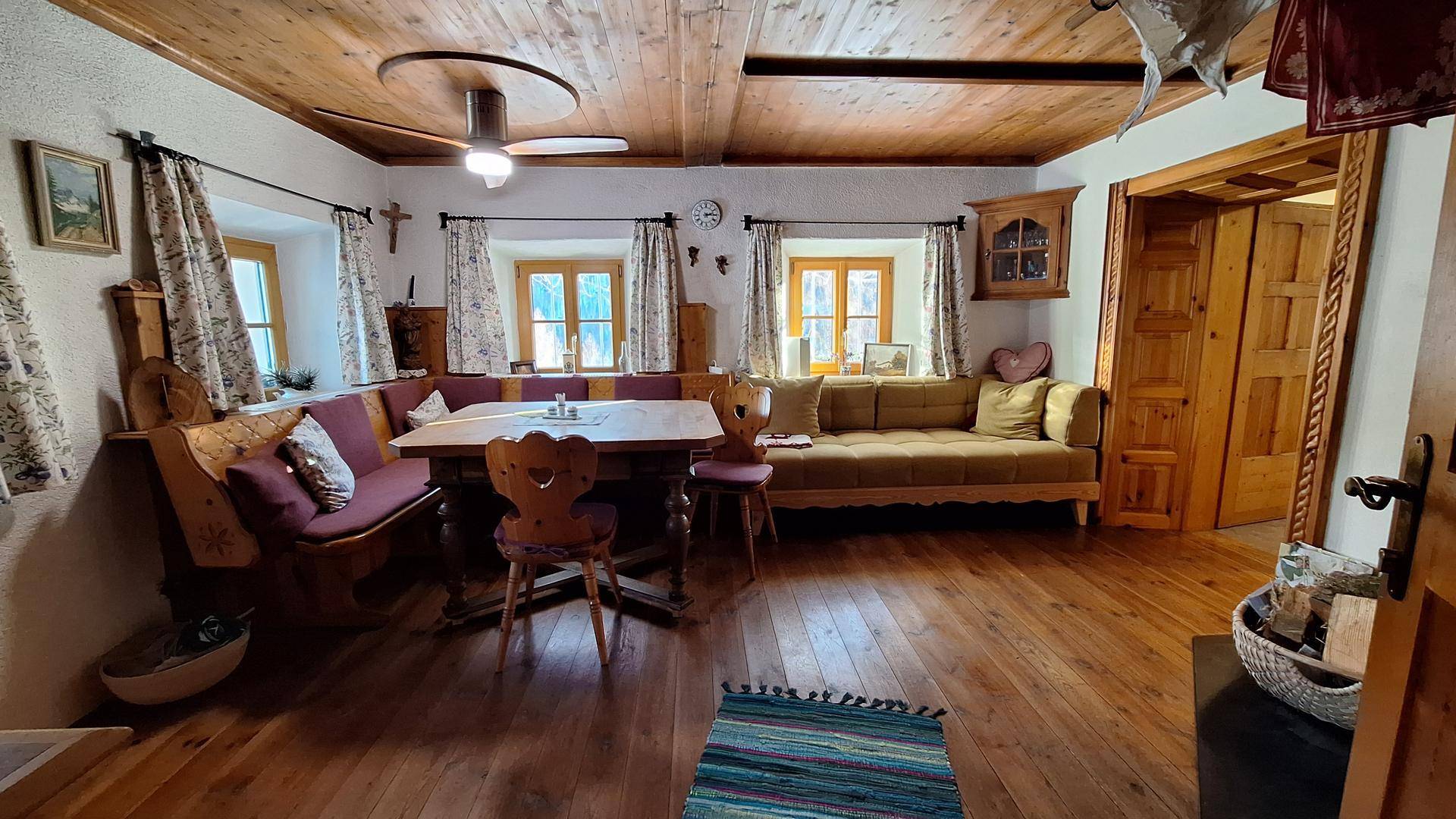 Gemütlicher Wohn-Essbereich im Landhausstil mit Holzboden, Holzdecke und traditionellen Möbeln.