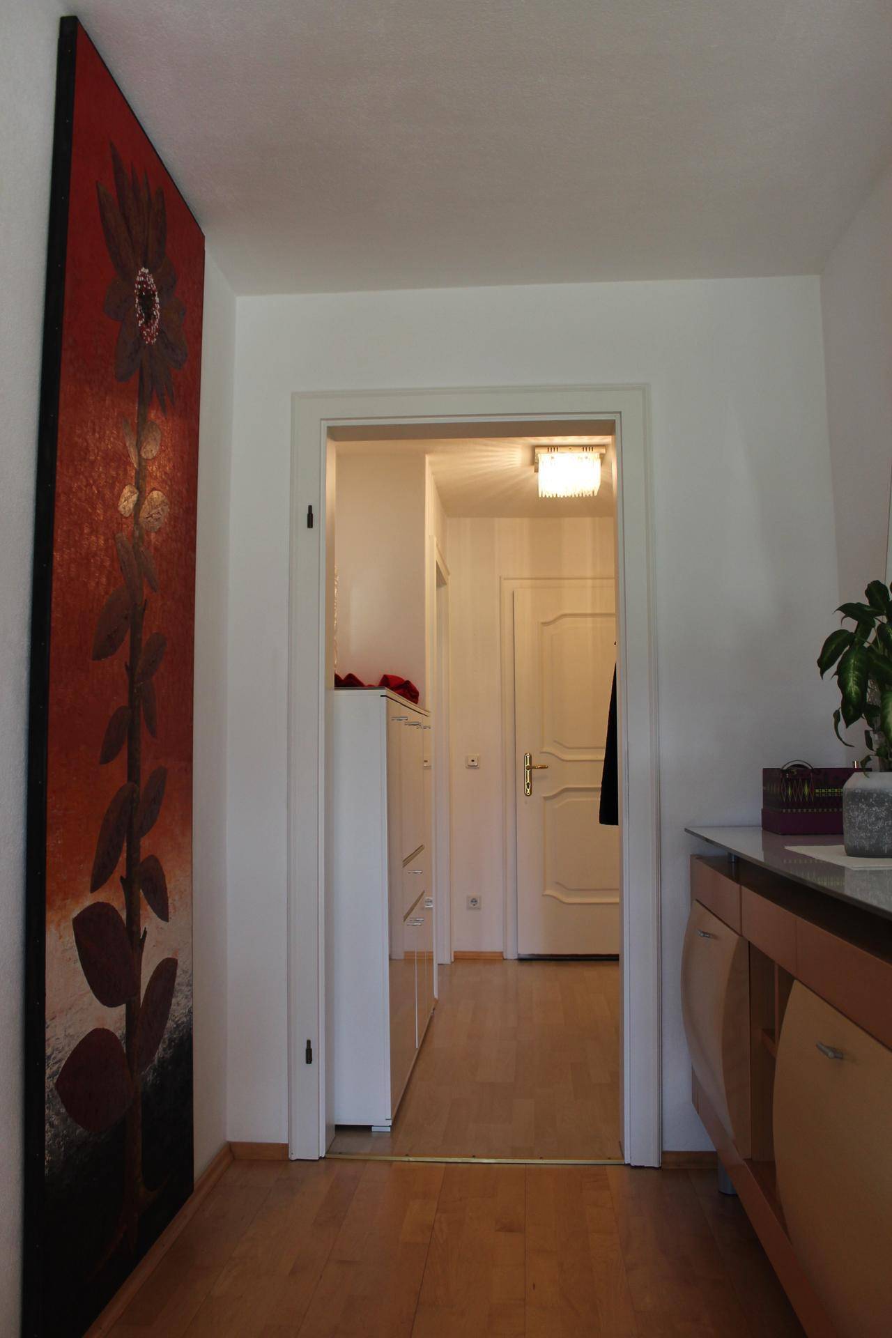 Heller Flur mit Holzboden und einem großen, roten Kunstwerk an der Wand.