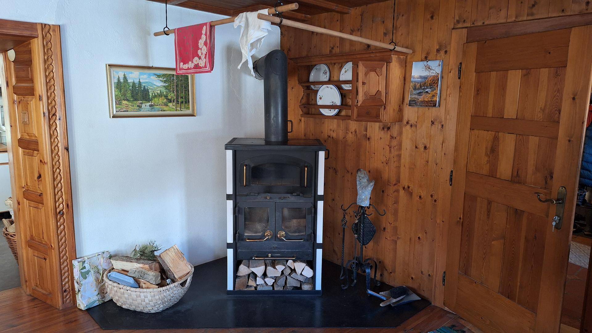Detailansicht eines modernen Holzofens mit Brennholz in einem rustikalen Wohnbereich.