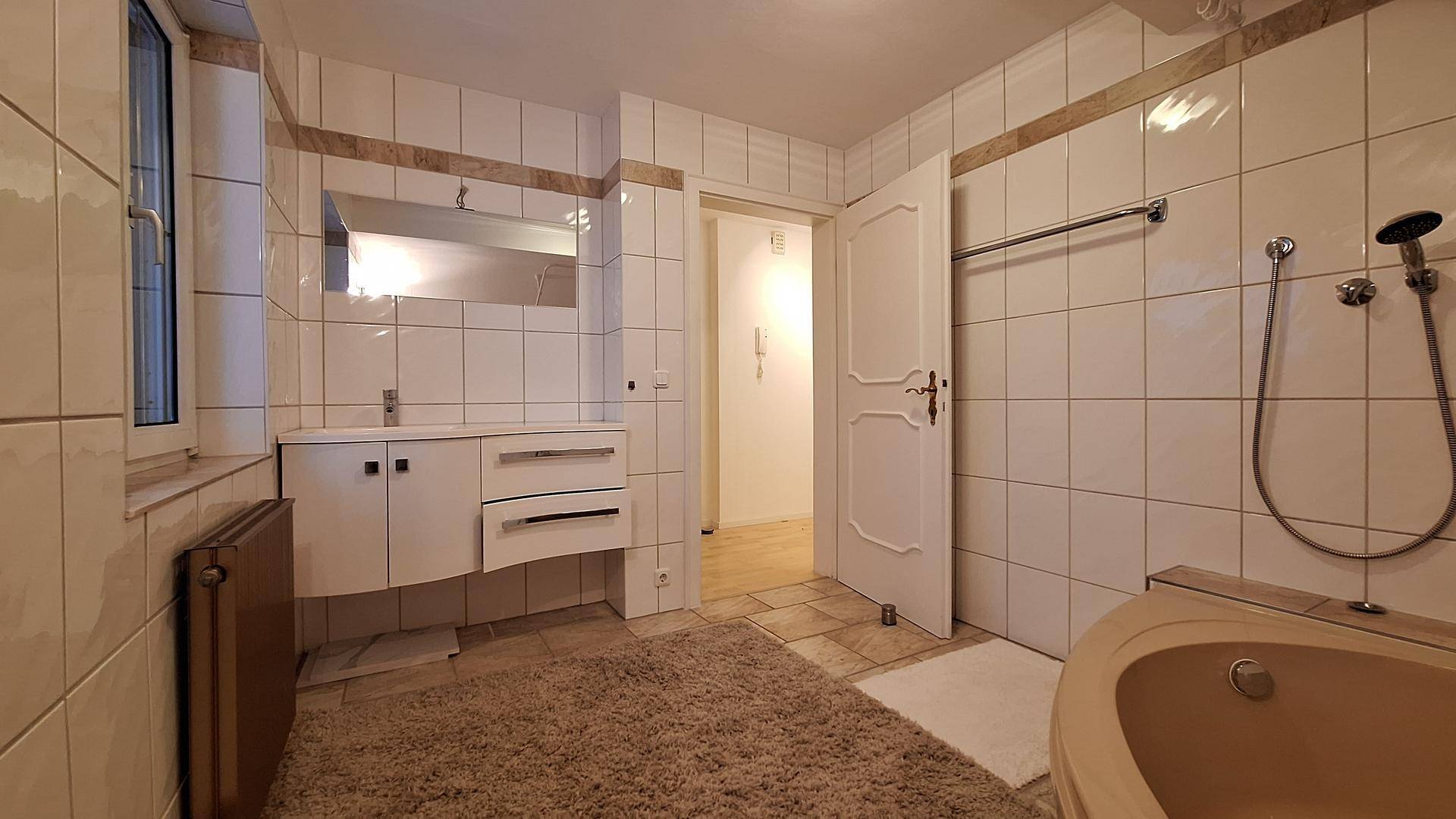 Geräumiges Badezimmer mit Eckbadewanne, Waschtisch und Fenster für natürliches Licht.