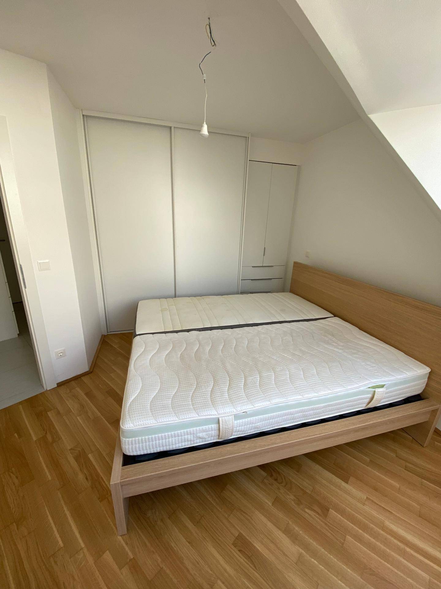 Geräumiges Schlafzimmer mit Holzboden und großem weißen Schiebetürenschrank.