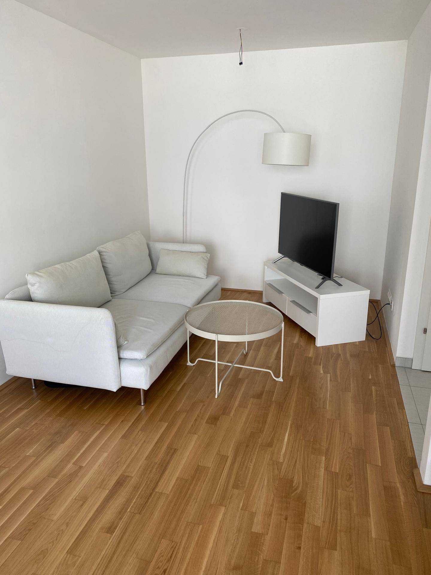 Gemütliches Wohnzimmer mit hellem Sofa, Holzboden und modernem Stehlampen-Design.