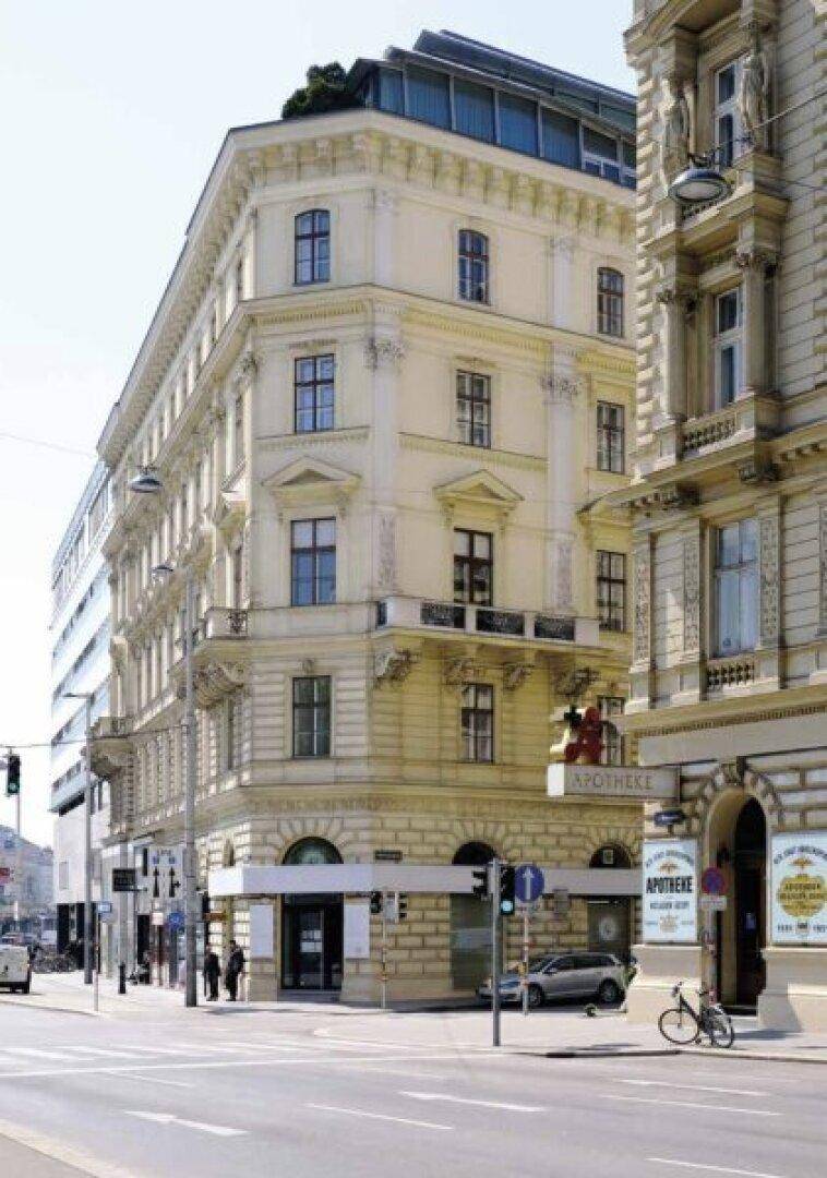 Prächtiges historisches Eckgebäude mit klassischer Fassade und Balkonen in einer belebten Stadtumgebung.