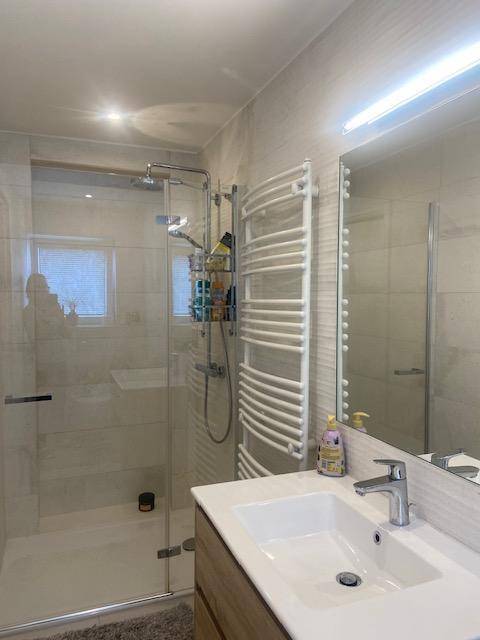 Modernes Badezimmer mit begehbarer Dusche, Einzelwaschbecken und beheiztem Handtuchhalter.