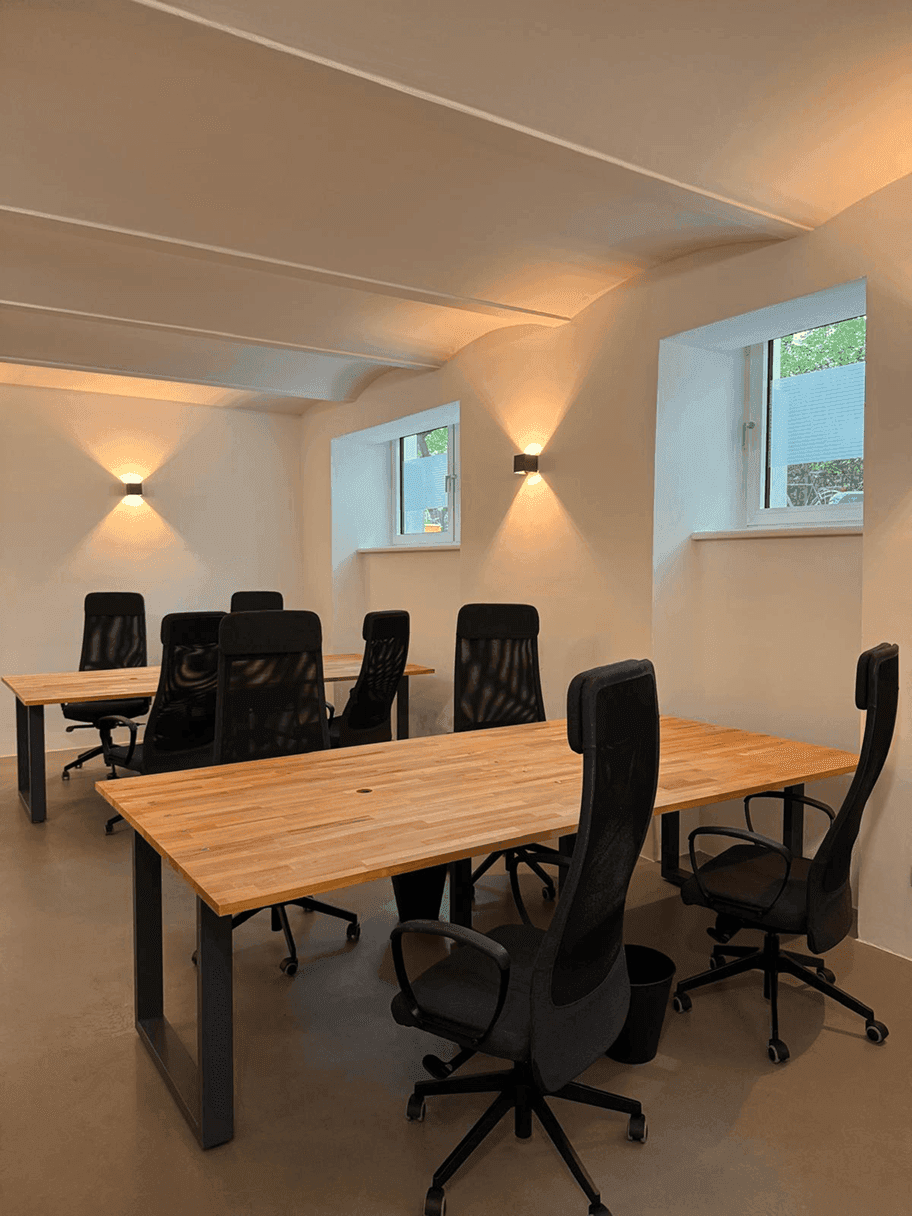 Heller Bürobereich mit mehreren Arbeitsplätzen, kleinen Fenstern und einer gewölbten Deckenstruktur.