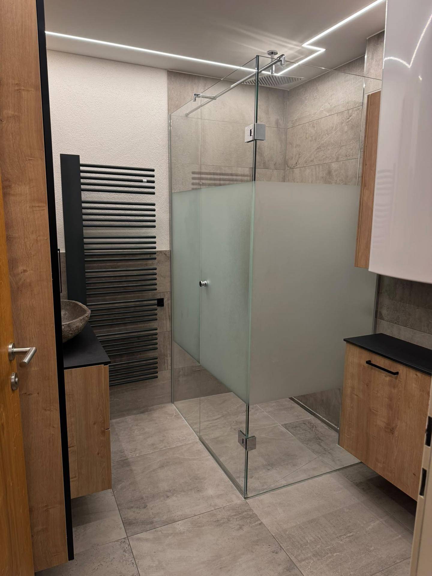 Geräumiges Badezimmer mit begehbarer Dusche, eleganter Glasabtrennung und modernen Armaturen.