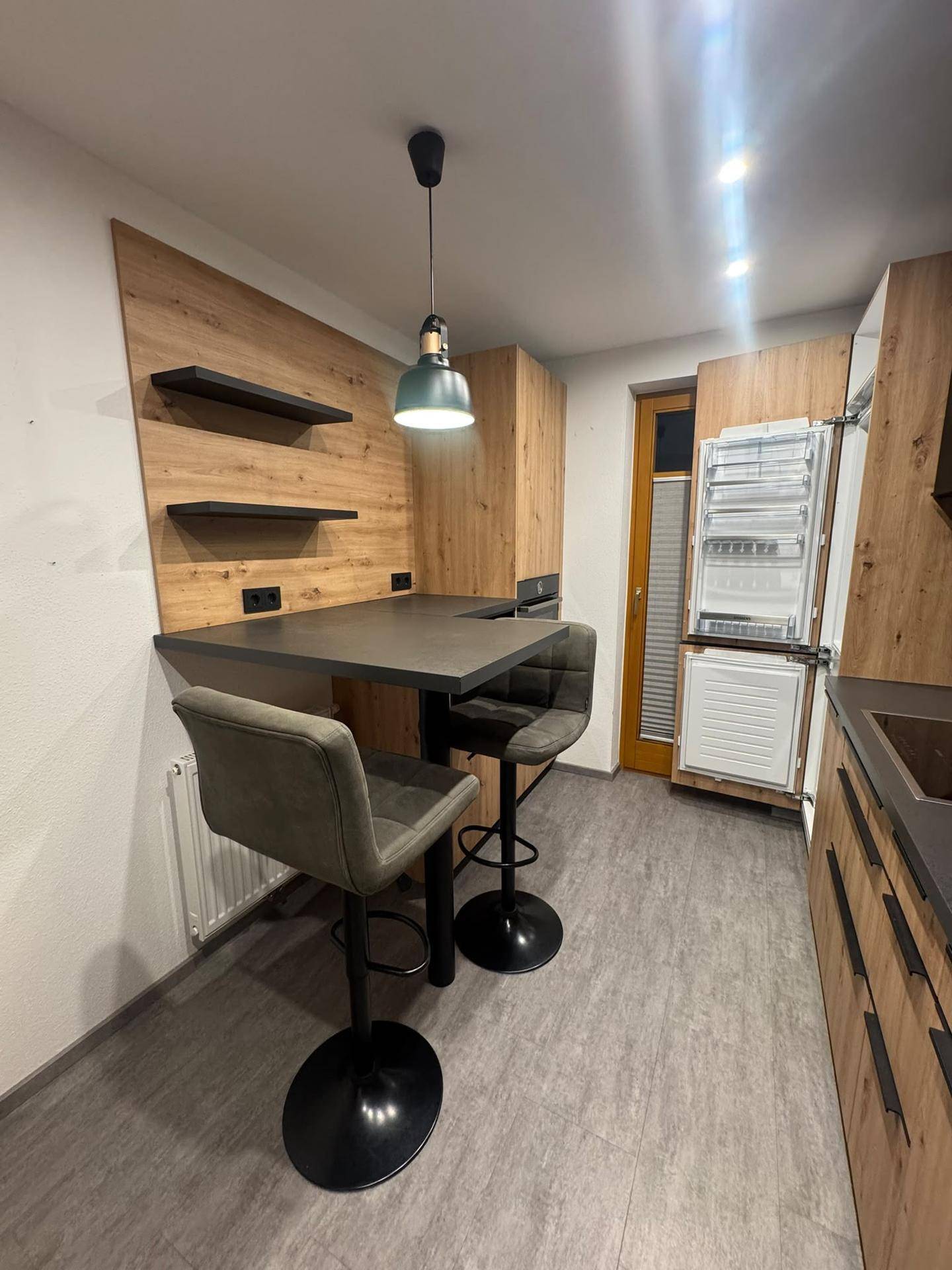 Küchenbereich mit Bartresen, Barhockern und Holzverkleidung an der Wand, ideal für schnelle Mahlzeiten.