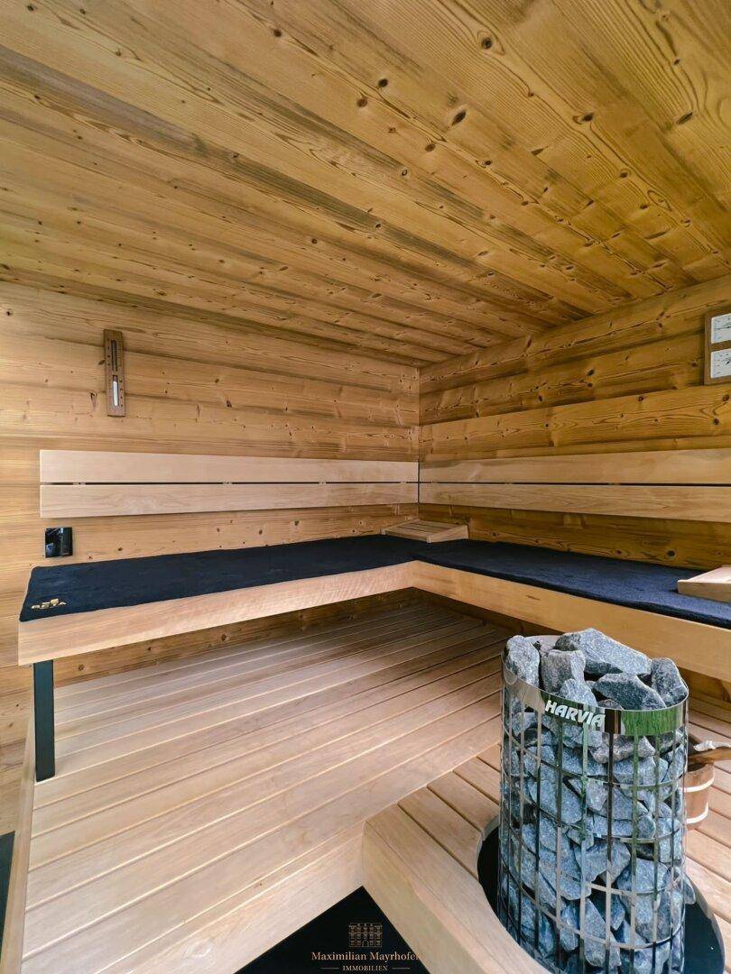 Innenansicht einer traditionellen Holzsauna mit Bänken und Saunaofen.