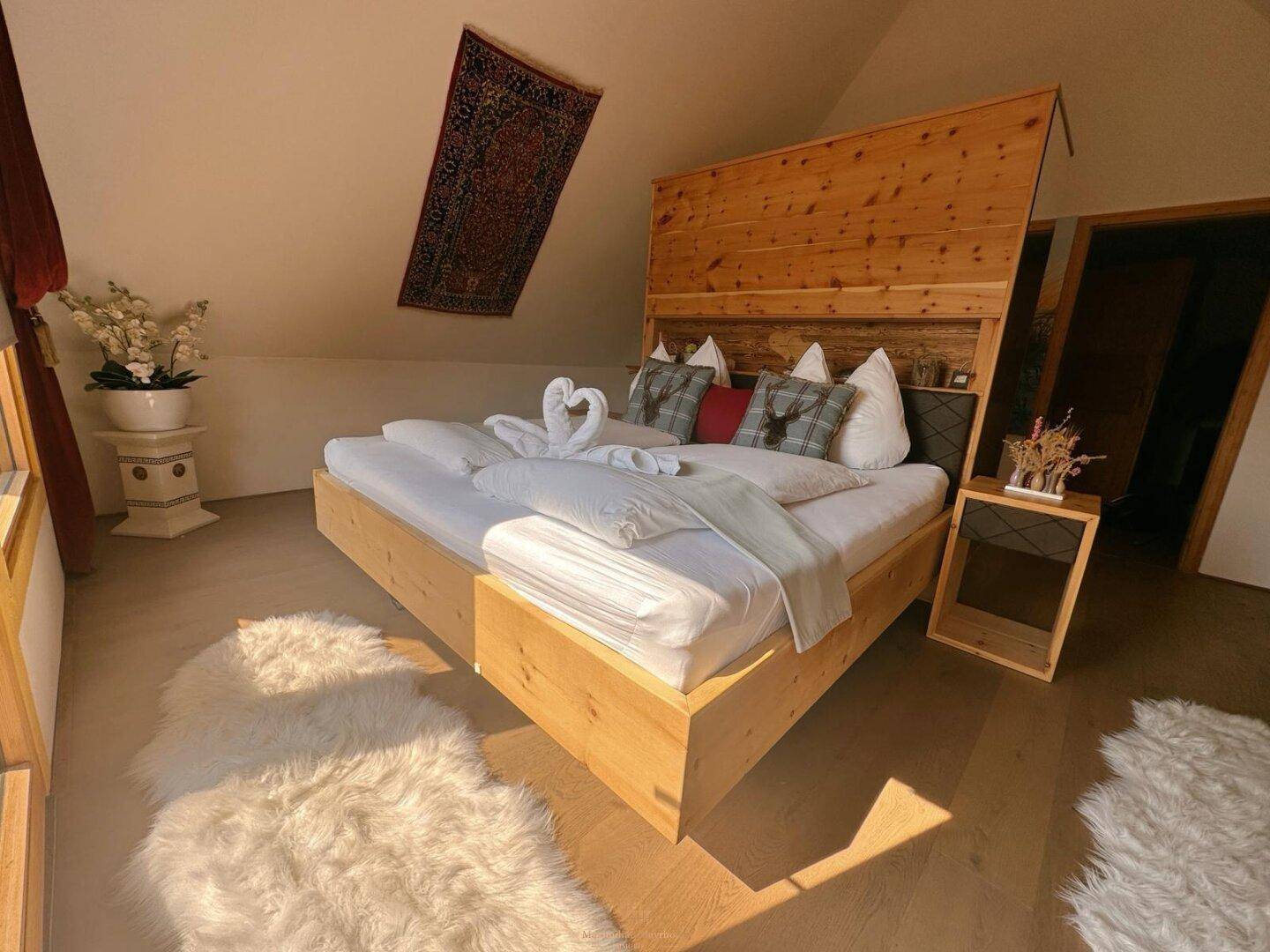 Helles Schlafzimmer mit Holzbett, Holzboden und Dachschrägen, gemütlich eingerichtet.