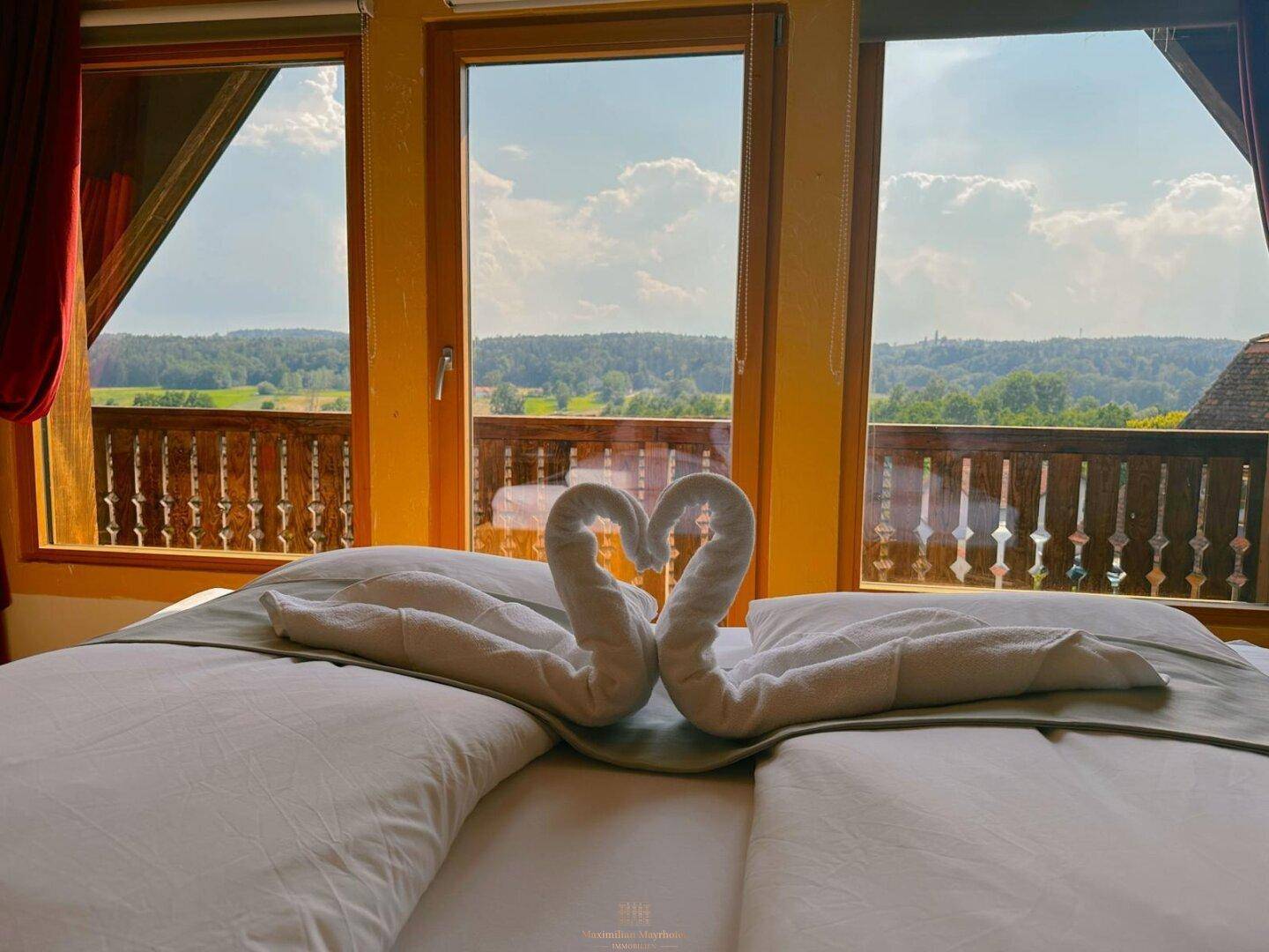 Schlafzimmer mit Doppelbett und weitem Panoramablick über die grüne Landschaft.