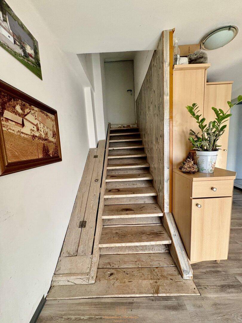 Treppenaufgang mit Holzstufen und einer Rampe, führt in die obere Etage des Hauses.