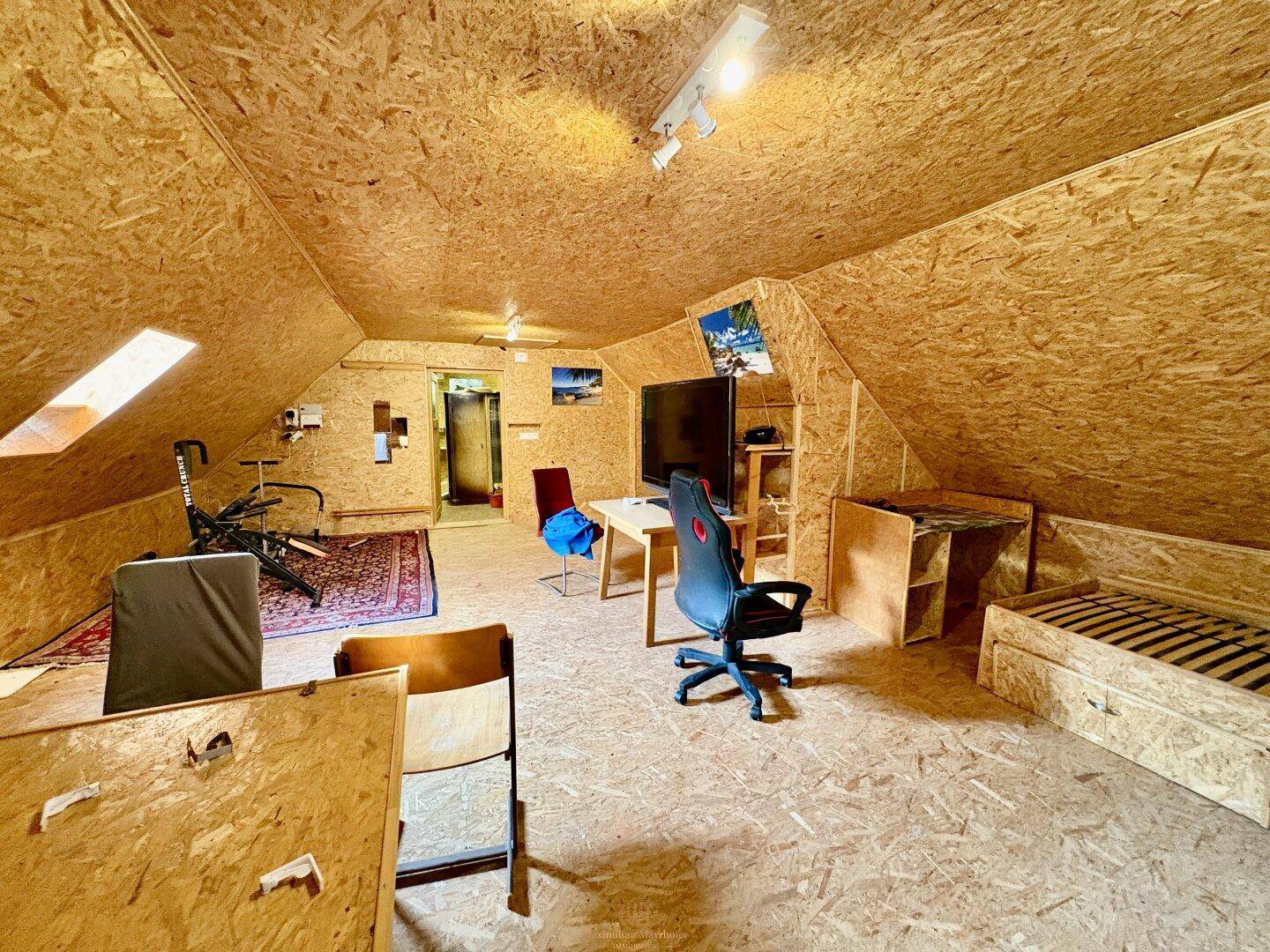 Geräumiger Dachboden mit Holzverkleidung und Schreibtisch, ideal für Büro oder Freizeitaktivitäten.
