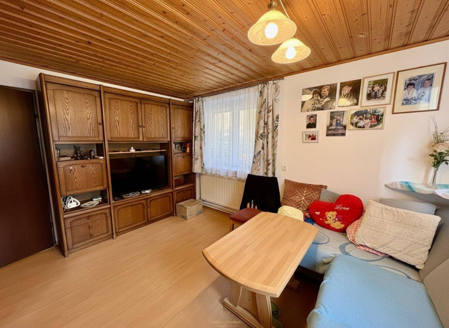 Gemütliches Wohnzimmer mit Holzdecke, traditionellen Möbeln und einem Sofa für entspannte Stunden.