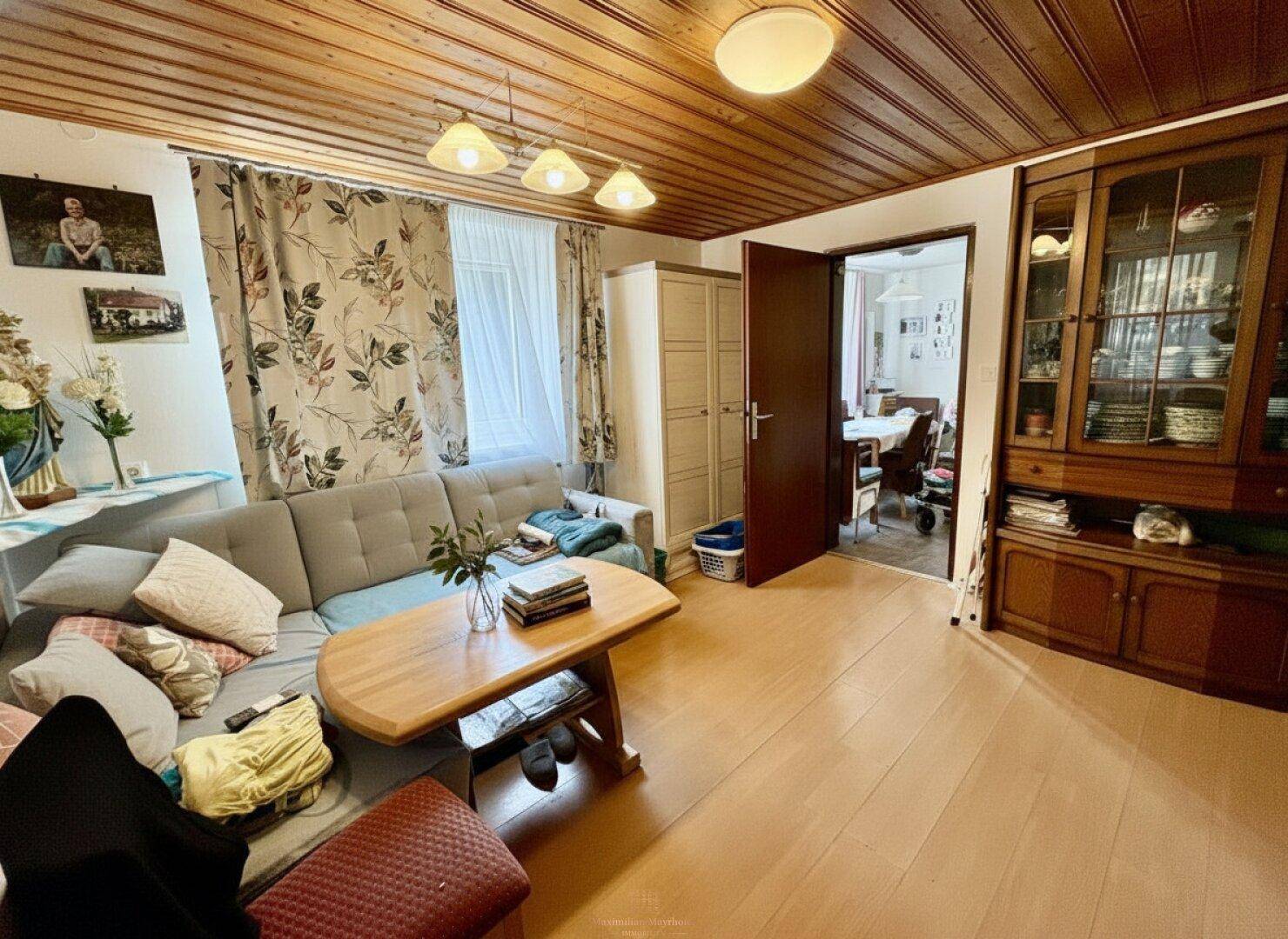 Wohnzimmer mit Holzdecke, bequemer Couch und traditionellen Holzmöbeln, bietet viel Platz.