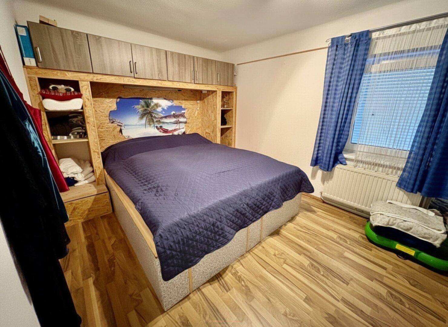Schlafzimmer mit Doppelbett und integrierten Holzschränken, bietet praktischen Stauraum.