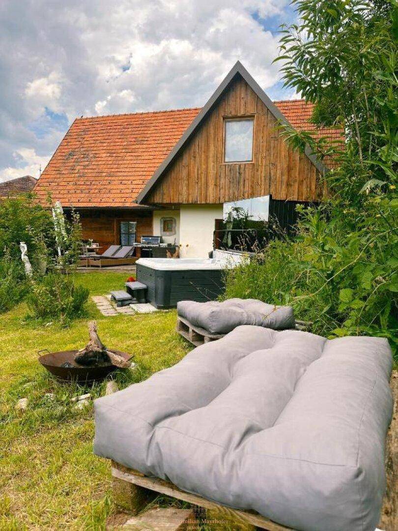 Entspannter Gartenbereich mit Palettenmöbeln, Feuerstelle und Blick auf das Haus.