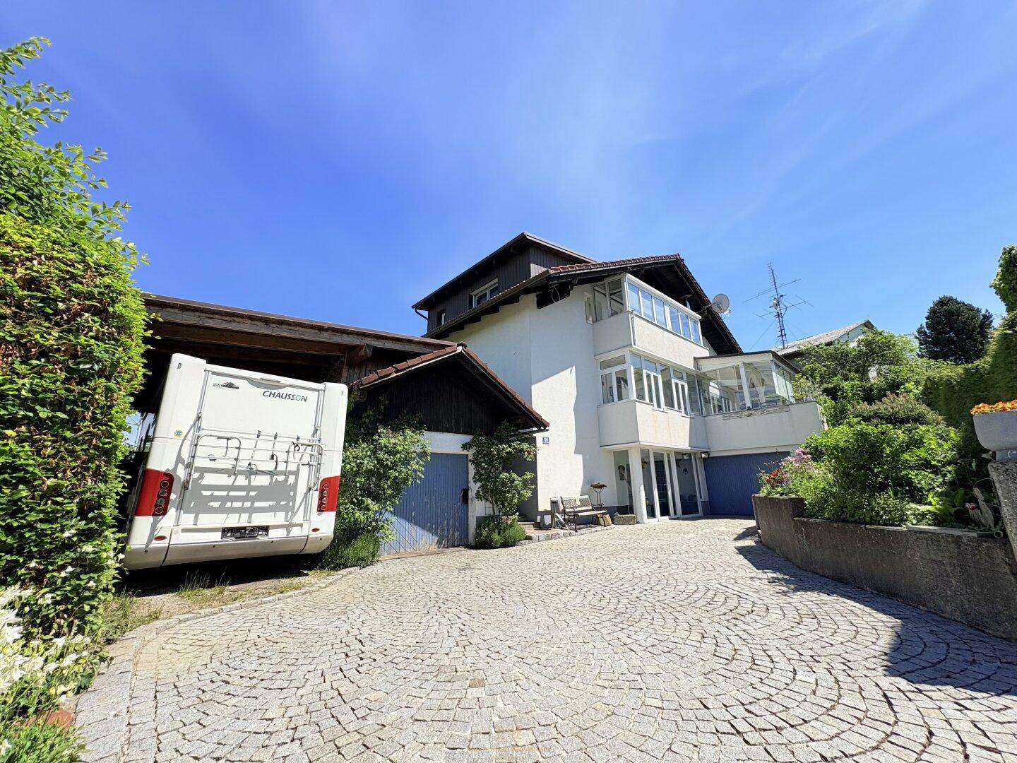 Vorderansicht des Hauses mit gepflasterter Auffahrt, Carport und einem Wohnmobil.