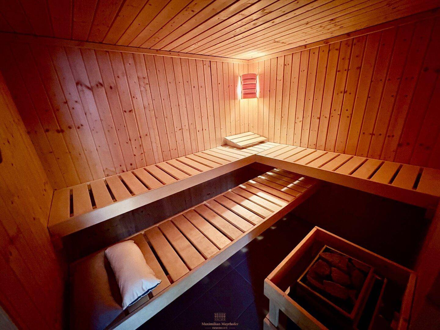 Gemütliche Holzsauna mit mehreren Bänken und indirekter Beleuchtung für Entspannung.