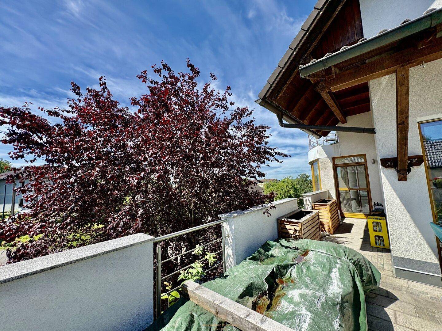 Balkon mit Metallgeländer und Blick auf die grüne Umgebung, teilweise überdacht.